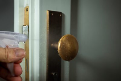 person spraying doorknob for Houston commercial cleaning