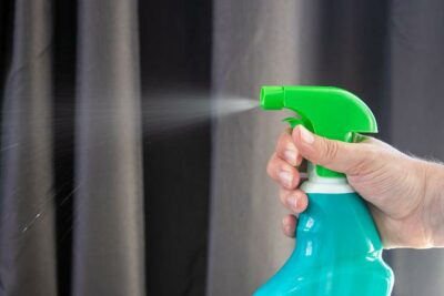 person holding spray bottle with cleaning chemicals for Houston commercial cleaning services