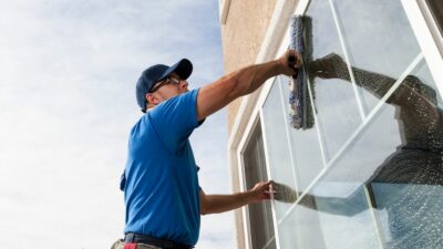 Crew member with Houston building cleaning washing exterior windows